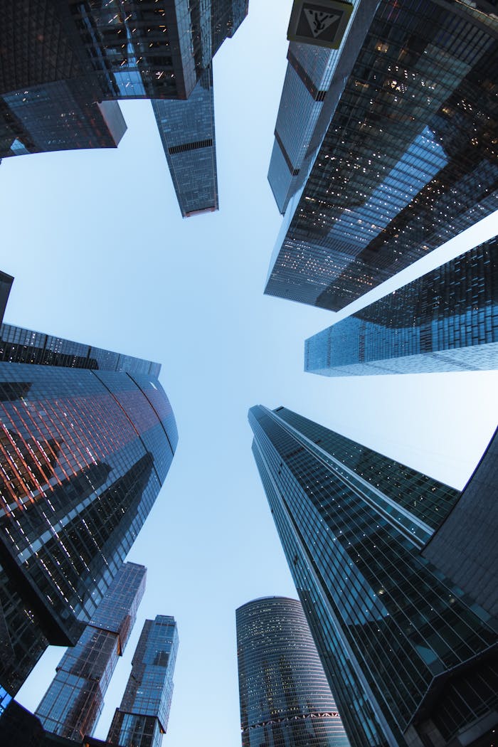 Looking up at modern skyscrapers forming a skyline against a clear blue sky.
